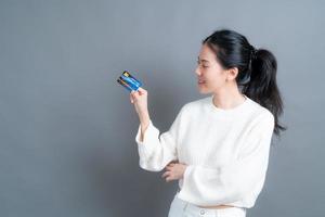 Portrait of a lovely young Asian woman in sweater showing credit card with copy space photo