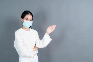 Mujer asiática con mascarilla médica protege el polvo del filtro pm2.5 anti-contaminación, anti-smog y covid-19 con presentación de la mano foto