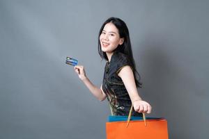 Mujer asiática vistiendo traje tradicional chino con bolsa de compras y tarjeta de crédito foto