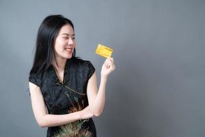 Mujer asiática vistiendo traje tradicional chino con la mano que sostiene la tarjeta de crédito foto