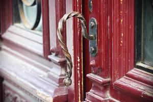 Gilded iron croocked door handle on red painted wooden door photo