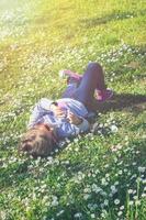 niña disfruta del día en el parque, recostada sobre el césped