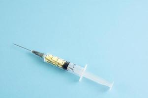 A medical syringe with yellow pills inside on blue background photo