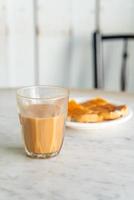 Vaso de té con leche tailandesa caliente en la mesa foto