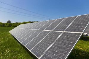 Estación de energía solar en la pradera de flores de verano foto