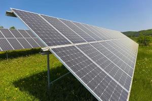 Estación de energía solar en la pradera de flores de verano foto