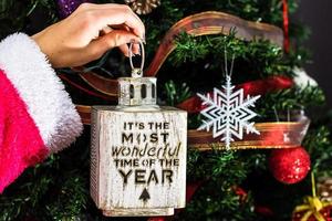 mano que sostiene el adorno de navidad delante del árbol de navidad foto