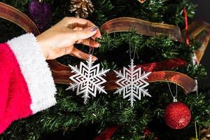 mano que sostiene el adorno de navidad delante del árbol de navidad foto