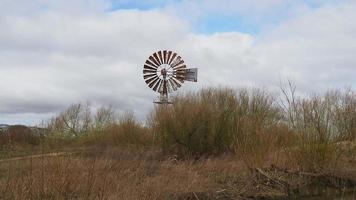 Wind pump in a field with its blades spinning in the breeze