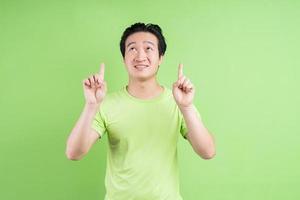 Portrait of asian man in green t-shirt posing on green background photo