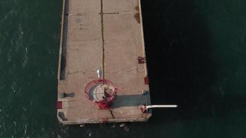Aerial shot of a red lighthouse at a long pier