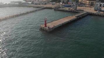 Aerial shot of a red lighthouse at a long pier