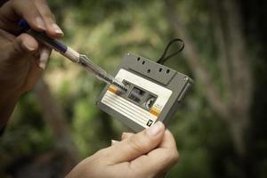 Las mujeres rebobinar una cinta de cassette vintage cassette compacto sobre fondo desenfocado, cerrar un conjunto de viejas cintas de audio, ret foto