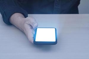 Glow lighting of phone in hands of guy. Close up of hand holding smart phone blank screen with glowing light effect. photo
