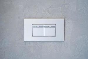 Grey light switch on the concrete wall. photo