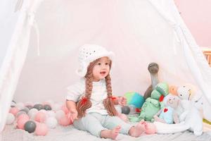 Little cute and adorable asian girl is playing with dolls in teepee tent. photo
