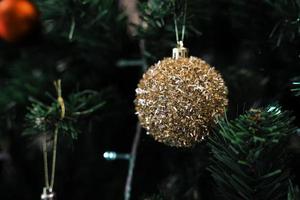 Golden Christmas balls on a green Christmas tree, close up. Christmas and New Year Decoration. photo