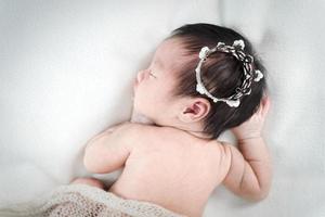 Newborn baby girl sleeping and wearing a silver crown. photo