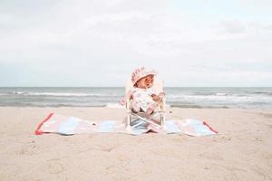 niña asiática sentada en la silla de playa y con gafas de sol. foto