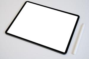 maqueta de tableta y lápiz digital con pantalla en blanco en blanco sobre mesa blanca.