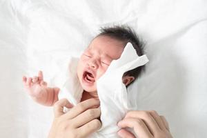 madre cambiando de ropa de bebé recién nacido llorando. foto