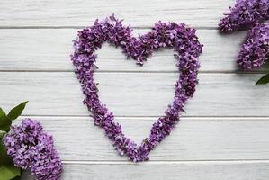 Marco de ramas y flores de color lila en forma de corazón. foto