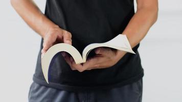 close-up da mão do homem em pé e abrindo um livro grosso.