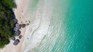 Vista aérea de la playa con sombra de agua azul esmeralda y espuma de olas en el mar tropical foto