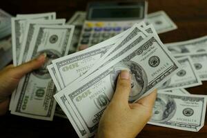 Businessmen women counting money on a stack of 100 US dollars banknotes photo