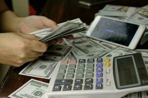 Businessmen women counting money on a stack of 100 US dollars banknotes photo