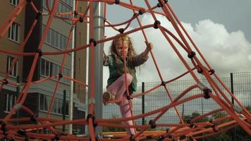 un niño se sube a una barra horizontal de cuerda en un patio de recreo al aire libre video
