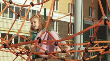 un niño se sube a una barra horizontal de cuerda en un patio de recreo al aire libre video