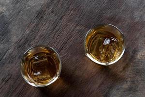 Top view of Whiskey with ice in glass on wooden table photo