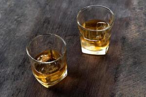 Top view of Whiskey with ice in glass on wooden table photo
