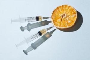 Minimal concept with a dried orange and two syringes photo