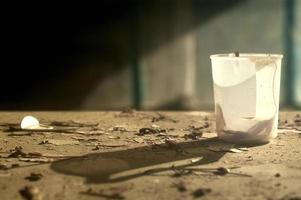 A still life image with an old plastic mug on a devastated table. Plastic mug with a hard shadow in warm colors. photo