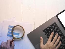 Magnifying glass and documents with analytics data lying on table,selective focus photo