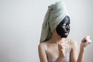 Bella mujer con máscara facial negra, concepto de estilo de vida foto