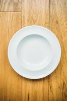 Empty white plate on wooden background photo