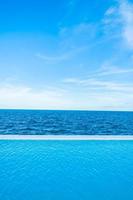 Infinity swimming pool with sea and ocean view on blue sky photo