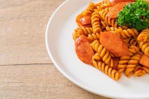 pasta en espiral o spirali con salsa de tomate y salchicha - estilo de comida italiana foto