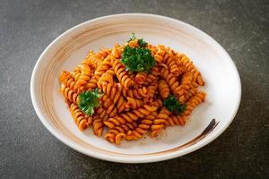 Spiral or spirali pasta with tomato sauce and sausage - Italian food style photo