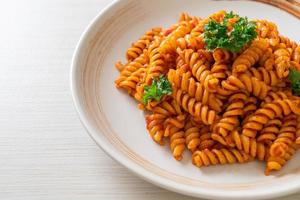 Spiral or spirali pasta with tomato sauce and sausage - Italian food style photo