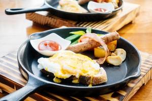 Egg benedict with sausage bacon and tomato sauce photo