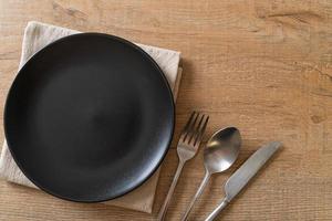 Empty plate or dish with knife, fork, and spoon on wood tile background photo