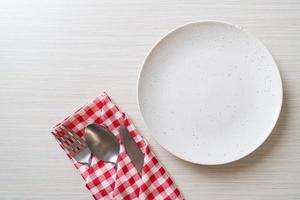 Empty plate or dish with knife, fork, and spoon on wood tile background photo