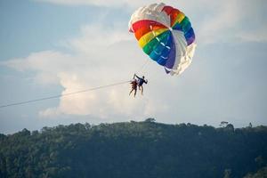 parasailing sobre el mar con un hermoso fondo de cielo azul en la playa de patong, phuket, tailandia. socus suave. foto