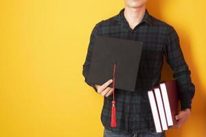 University man is happy with graduation on yellow background photo