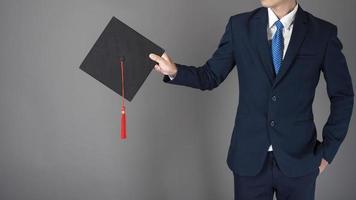 El hombre de negocios está sosteniendo un sombrero de graduación, concepto de educación empresarial foto