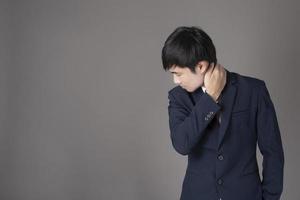 Business man is having neck pain ,grey background in studio photo